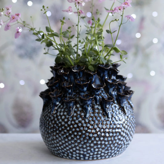 Decorative vase with textured surface and floral arrangement on a blurred background