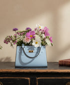 Blue handbag filled with flowers on a white background
