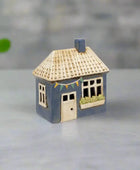 Small model of a house with a blue base and beige roof on a white background