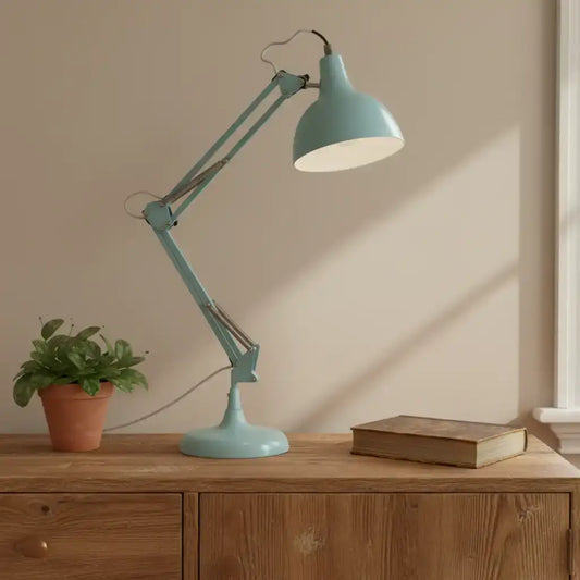 Teal desk lamp on a wooden surface with a plant and book in the background