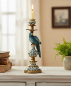 Decorative candlestick with a bird figurine on a table with books and a plant.