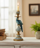 Decorative candlestick with a bird design on a table next to books and a plant.