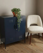 Navy blue metal cabinet with a plant next to a beige chair on a wooden floor.