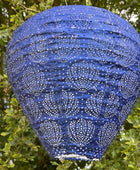 Blue paper lantern with white patterns hanging among green leaves