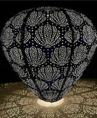 Decorative lamp with intricate cut-out design casting shadows on a surface