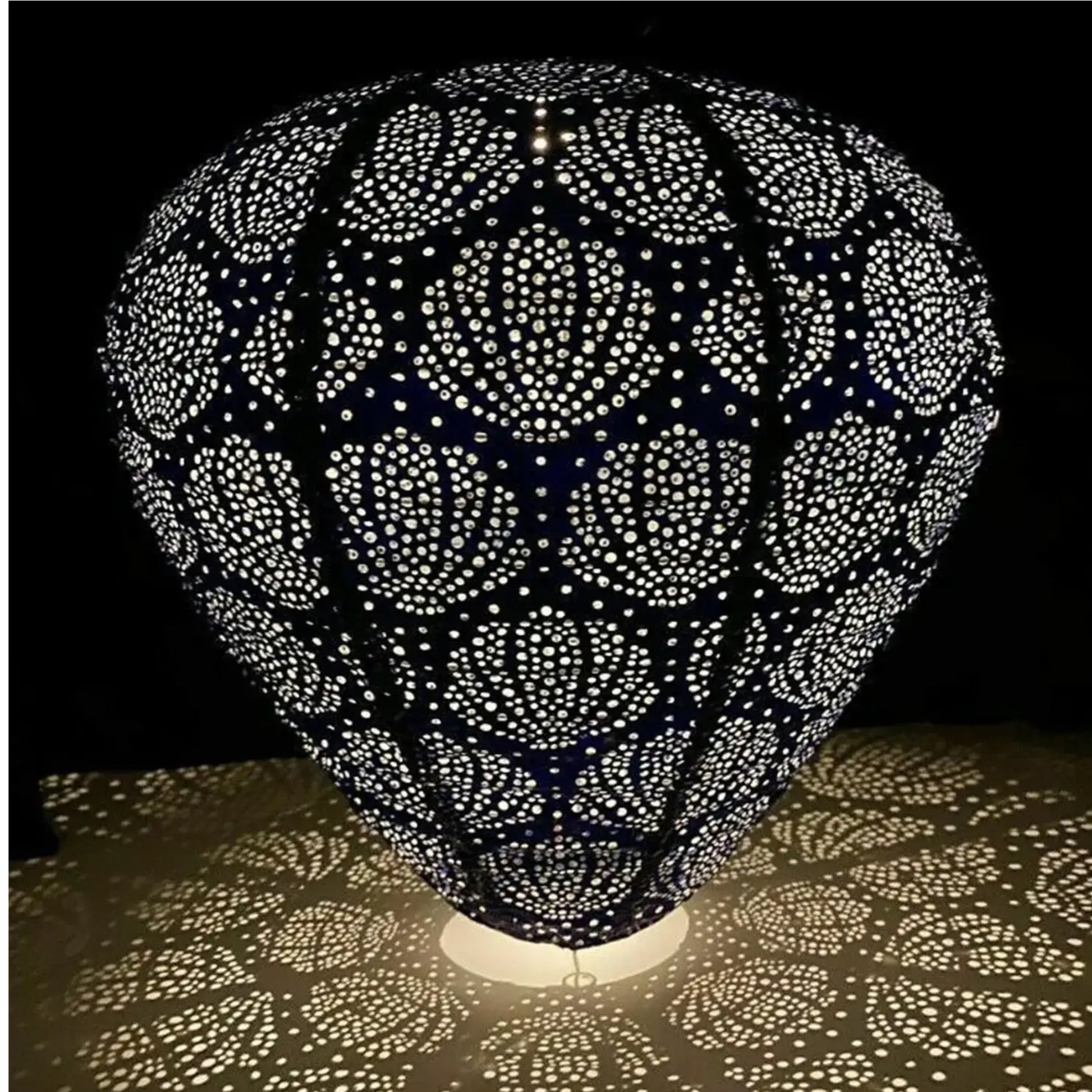 Decorative lamp with intricate cut-out design casting shadows on a surface