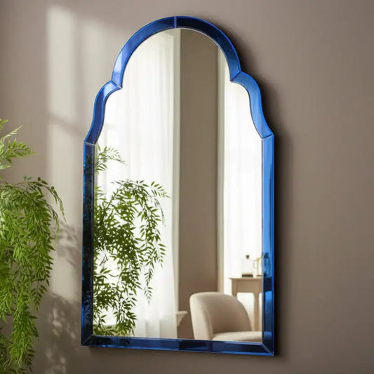 Blue-framed mirror on a wall with a plant in the foreground