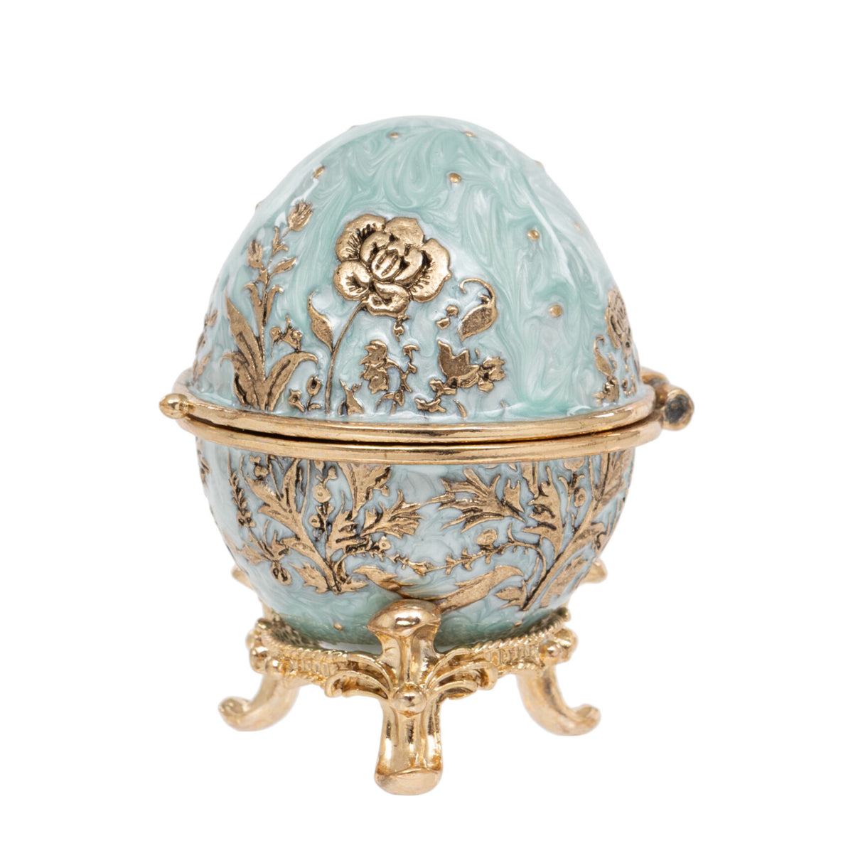 A decorative egg-shaped box with a light aqua enamel finish and ornate gold-tone floral engravings, resting on a matching gold-tone stand against a plain white background.