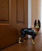 Dog-shaped doormat on a wooden floor with a wooden door in the background