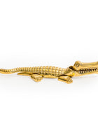 A gold-finished alligator-shaped accessory, likely a brooch or pin, shown against a plain white background.