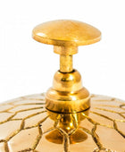 Close-up of a gold decorative object with intricate patterns on a white background