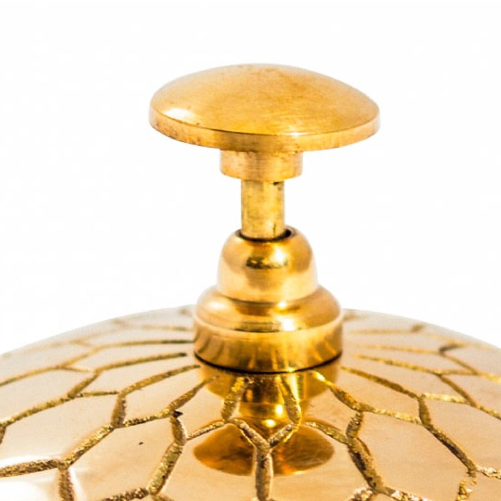 Close-up of a gold decorative object with intricate patterns on a white background