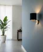 Modern interior with a wall lamp, plant, and white curtains.