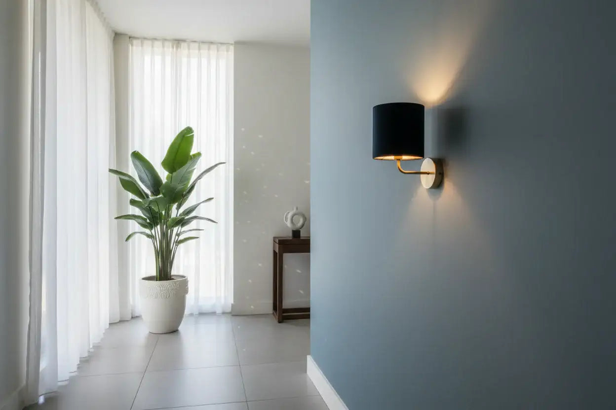 Modern interior with a wall lamp, plant, and white curtains.