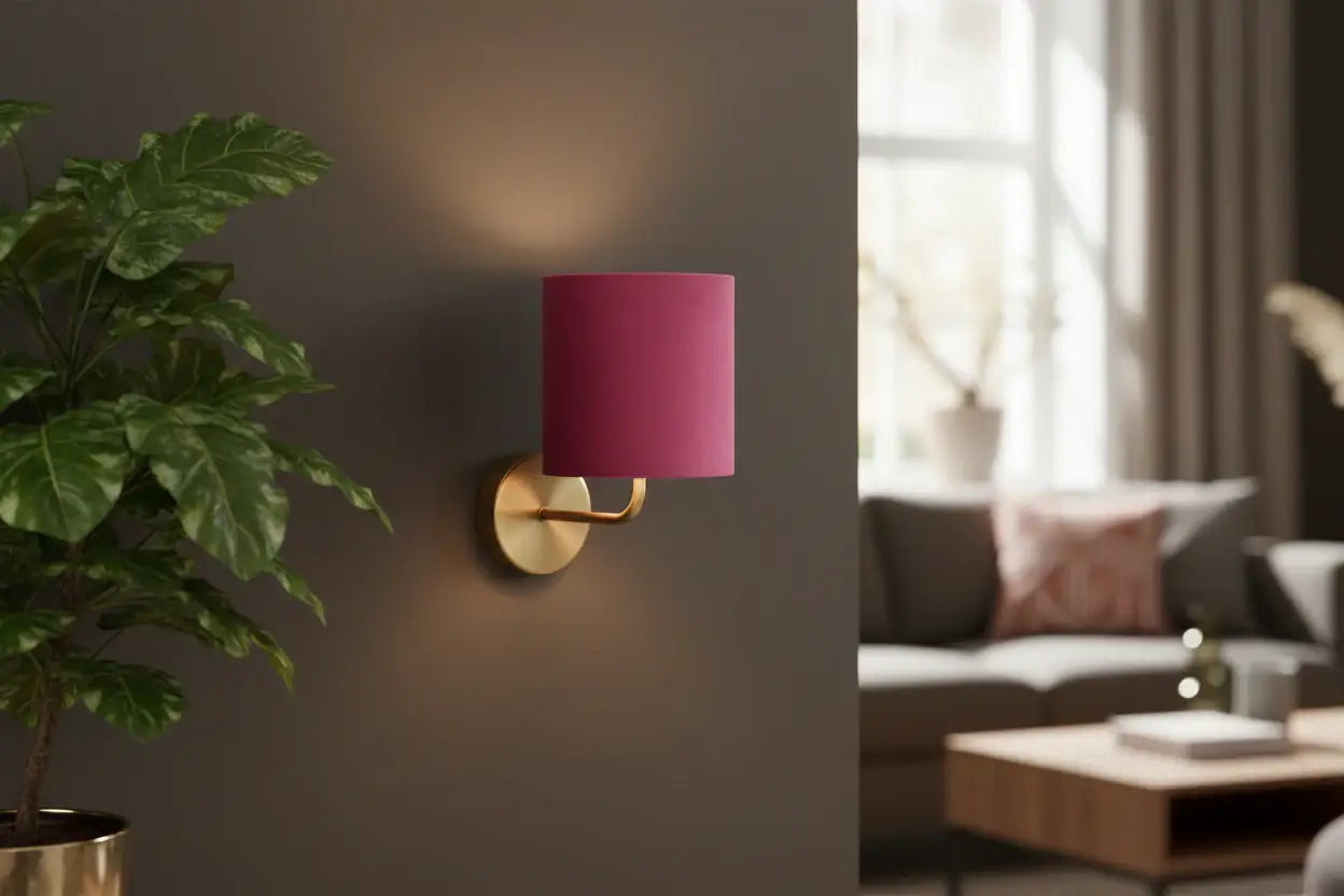 Wall-mounted lamp with pink shade on a gray wall next to a living room setting.