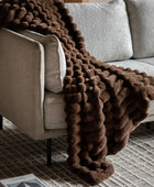 Brown textured blanket draped over a beige sofa in a living room setting.