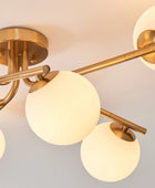 Gold ceiling light fixture with glass globe shades on a neutral background