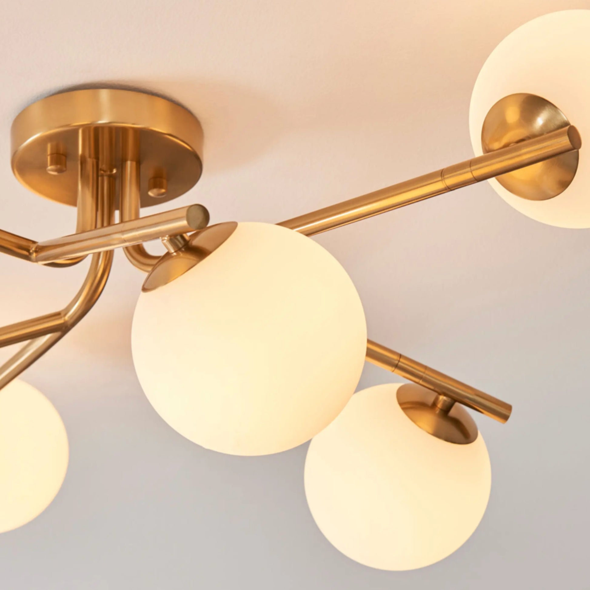 Gold ceiling light fixture with glass globe shades on a neutral background