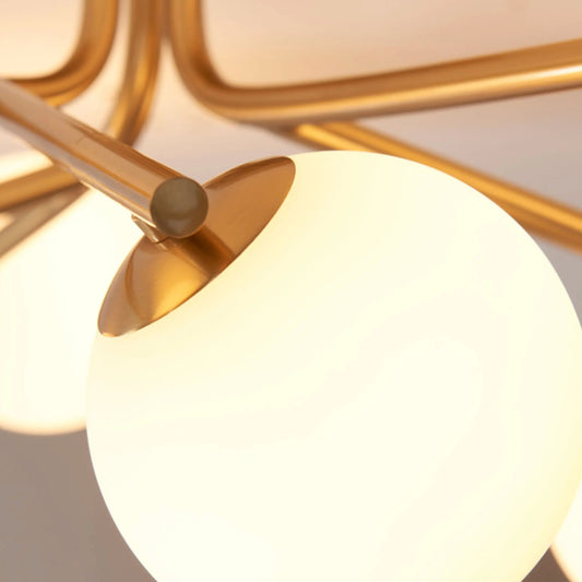 Close-up of a modern ceiling light fixture with gold accents and white glass shades.