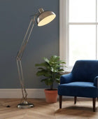 Blue armchair next to a floor lamp and potted plant in a room with a window.