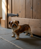 Dog figurine standing on a tiled floor in front of a wooden door.