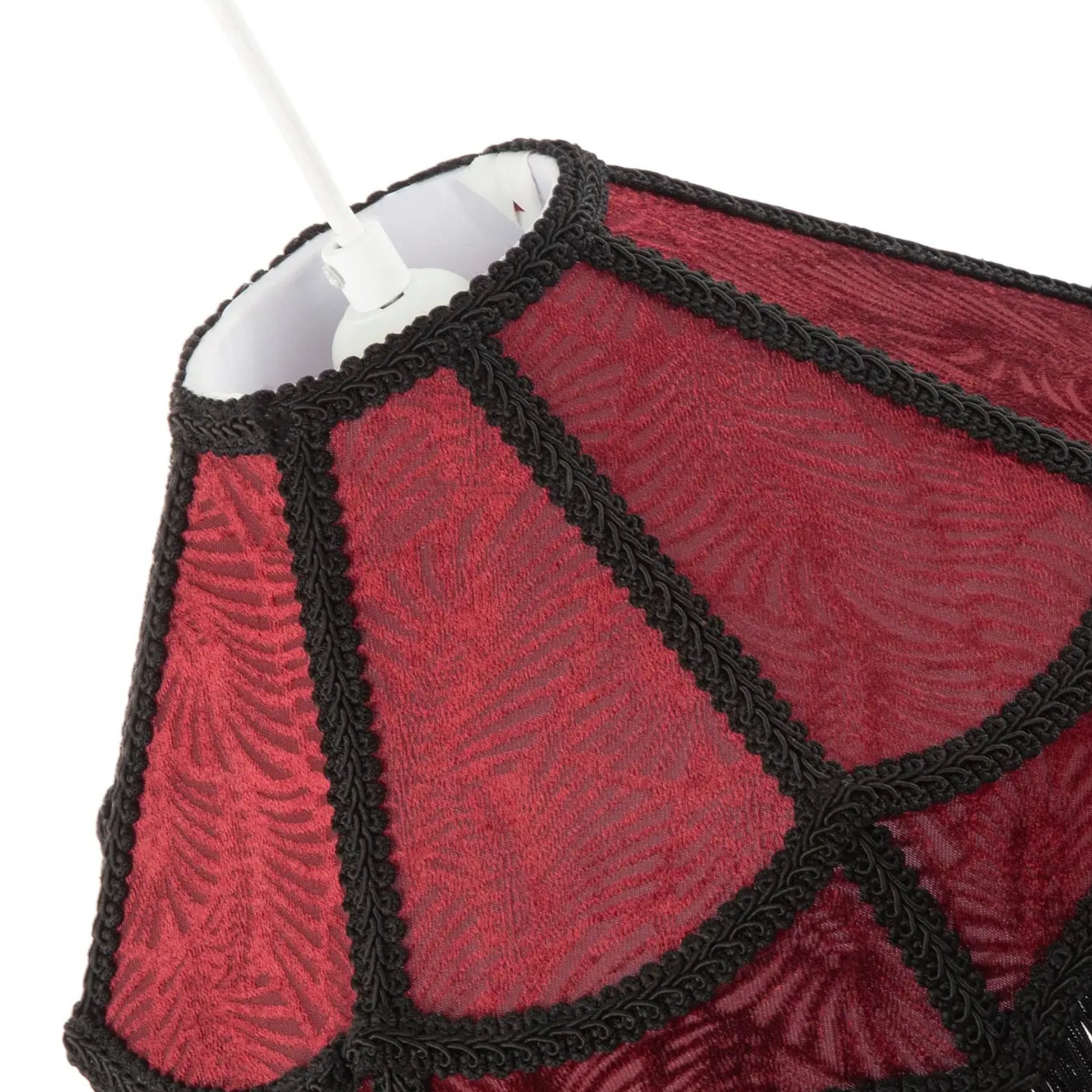 Close-up of a red patterned fabric lampshade with black braided trim and a white hanging cord visible at the top, photographed against a white background.