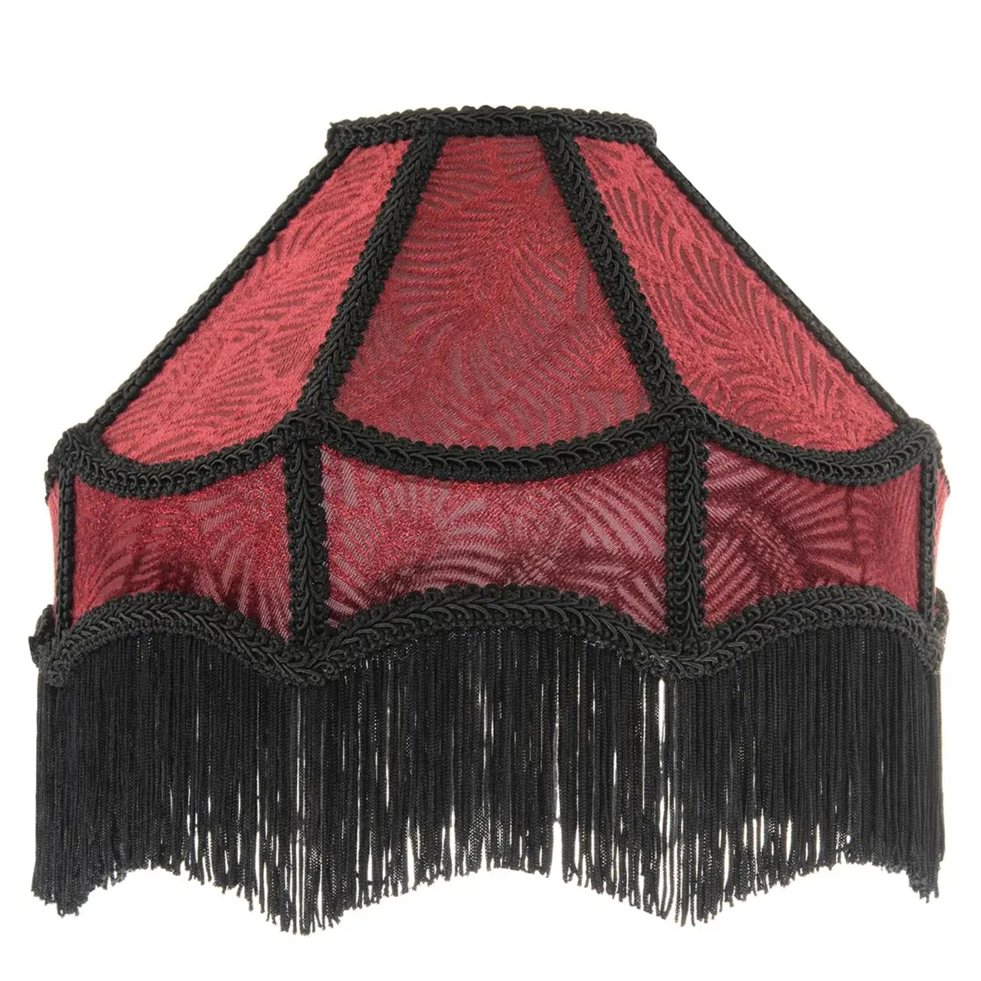 A vintage-style fabric lampshade with a red patterned body, black braided trim, and a long black fringe along the bottom edge, shown against a plain white background.
