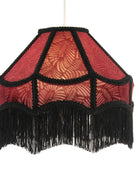A vintage-style hexagonal pendant lampshade with a red patterned fabric body, black braided trim, and a long black fringe hem, suspended against a plain white background.