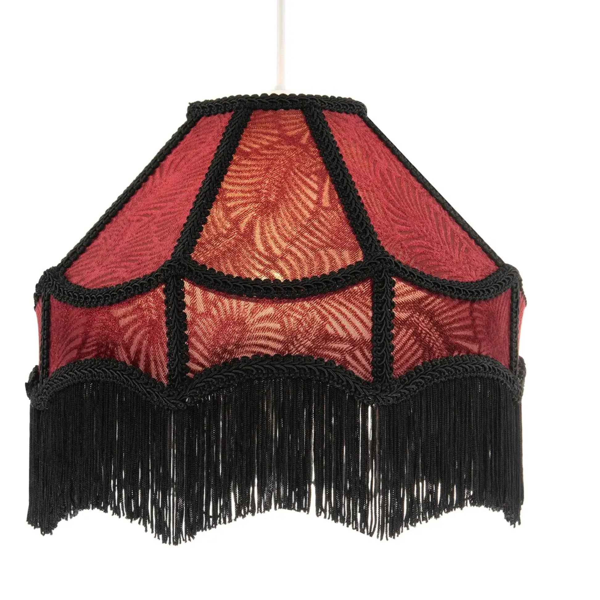 A vintage-style hexagonal pendant lampshade with a red patterned fabric body, black braided trim, and a long black fringe hem, suspended against a plain white background.