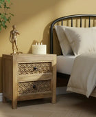 Wooden nightstand with decorative items next to a bed in a bedroom setting.