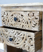 Wooden drawer with intricate carvings and dark knobs on a light background