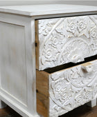 White wooden dresser with intricate carvings on a plain background