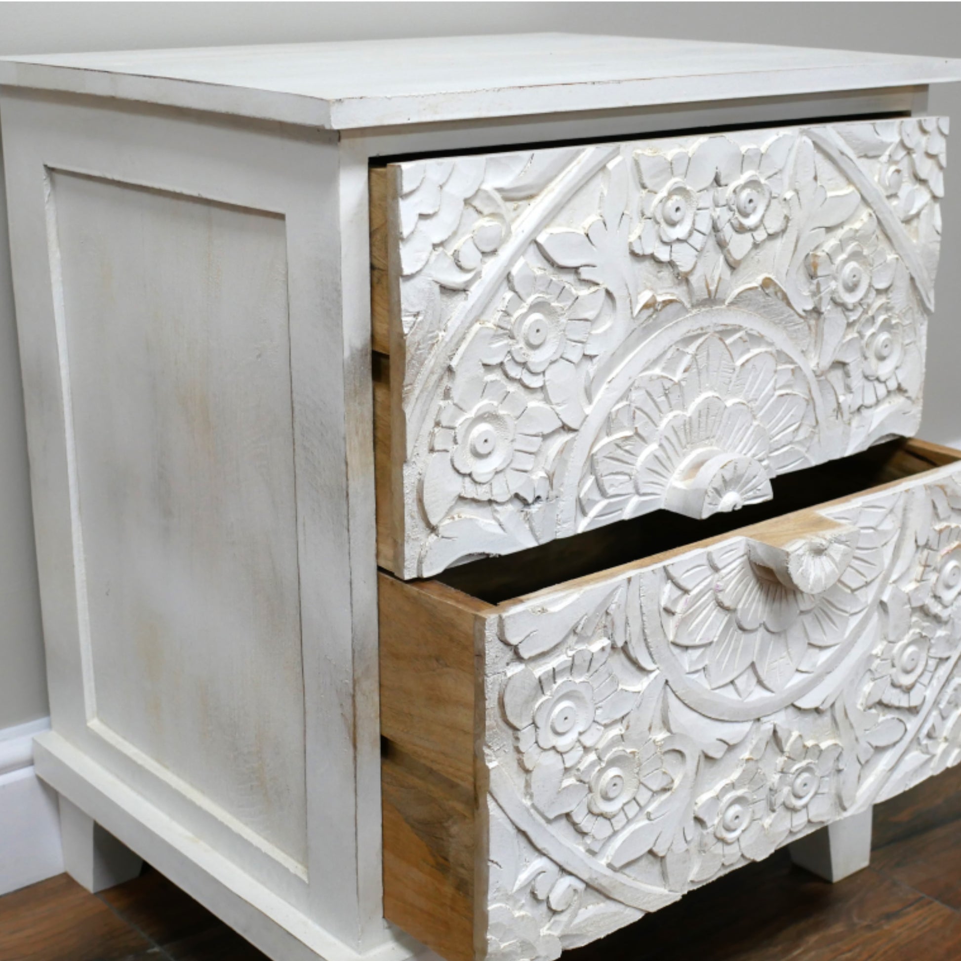 White wooden dresser with intricate carvings on a plain background