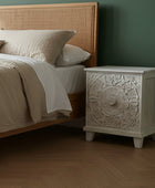 White decorative cabinet with intricate carvings on a wooden floor.