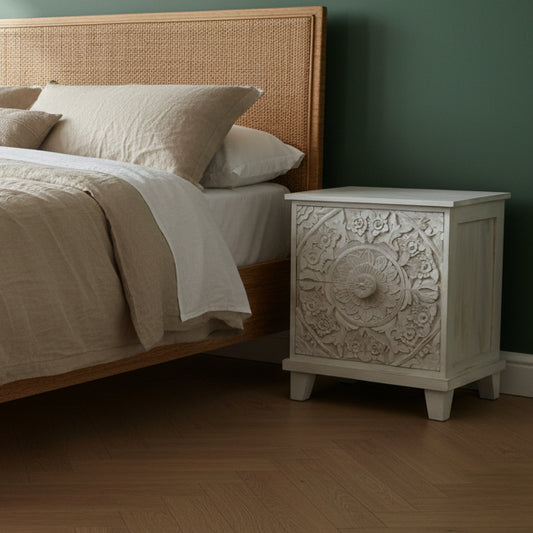 White decorative cabinet with intricate carvings on a wooden floor.