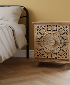 Bedroom with a bed and a wooden nightstand with intricate carvings.