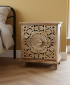 Wooden nightstand with intricate carvings in a bedroom setting