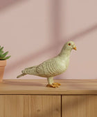 Decorative pigeon figurine on a wooden surface with a pink background