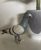 Statue of a pigeon next to a pot on a light surface