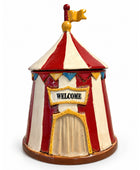 A small circus tent shaped container or decorative piece with red and cream vertical stripes, a gold-trimmed front door, a 'WELCOME' sign, and a gold flag on top, photographed on a plain white background.