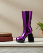 Shiny purple boot on a white surface with books and a plant