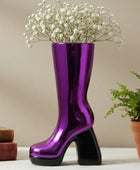 Purple boot-shaped vase with white flowers on a neutral background