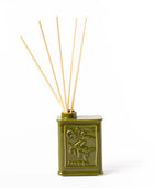 Olive green ceramic reed diffuser bottle with embossed lettering and five natural wood reeds, shown on a white background.