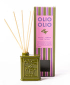 Olio Olio reed diffuser set featuring an olive green tin bottle with natural reed sticks, positioned in front of its pink and green striped packaging box on a white background.