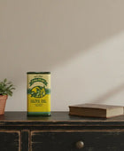 Vintage olive oil can on a wooden surface with a plant and book