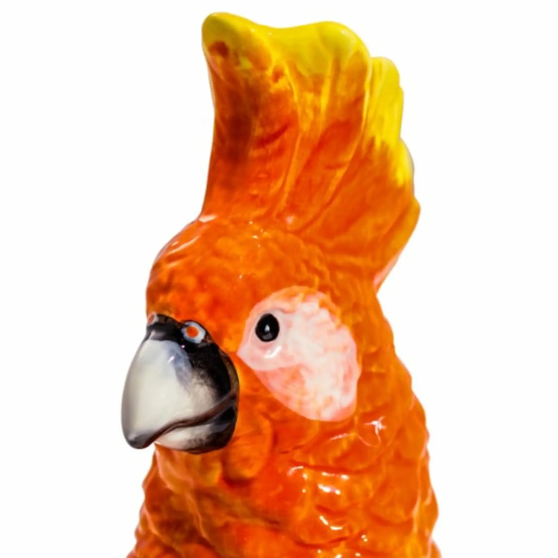 Close-up of a ceramic parrot figurine with orange and yellow feathers on a white background