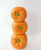 Three stacked oranges with green stems on a white background