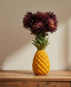 Pineapple with a flower arrangement on a wooden surface