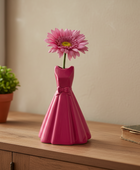 Pink dress-shaped vase with a pink flower on a wooden surface