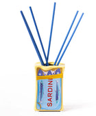 A Sardinian-themed reed diffuser with a yellow and blue tin container printed with sardines and the word 'SARDINI', filled with five blue reeds, on a white background.